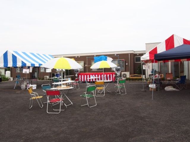 屋外イベントスペース イベント カラフルなテントと椅子が並ぶ広々とした開放的な空間です。屋外でのアクティビティや交流が楽しめる環境が整っています。