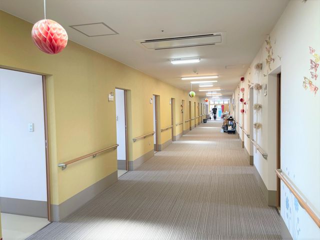 明るく清潔な廊下 通路 ゆったりとした空間が確保された廊下です。壁に飾られた花の装飾が、訪れる人々に温かみを感じさせます。