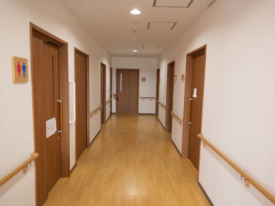幅の広い廊下である。左右に並んでいるトイレや居室の扉には、引き戸が採用されている。手すりが壁に沿って設置されている。