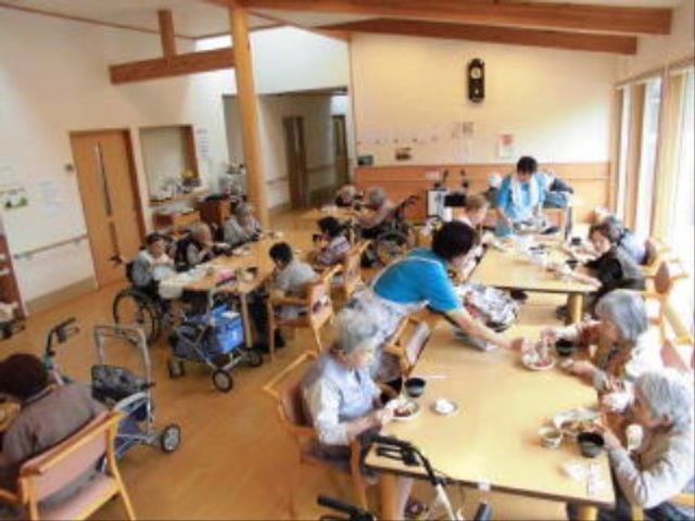 共有スペースでのお茶会 共有スペース ゆとりあるダイニングで、利用者同士が穏やかなお茶の時間を過ごしています。コミュニケーションを大切にした温かな雰囲気が感じられます。