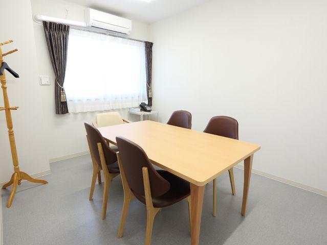 シンプルな居室 談話室 開放感のある居室で、機能的な家具が配置され、日々の業務を行う環境が整っています。清潔感のある空間で快適に過ごせそうです。