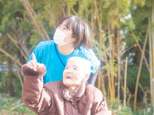 外の光浴びる高齢者と職員