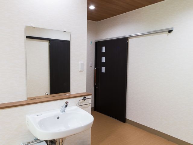 洗面台と扉のある廊下 居室 清潔感のある洗面台が完備された廊下です。壁には手すりが設置され、安全に配慮されています。