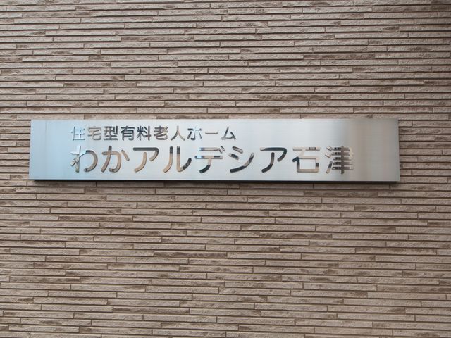 壁に取り付けられた施設の看板 看板 洗練されたデザインの看板が印象的な場所で、目に留まりやすく、施設の顔として訪問者を迎えます。