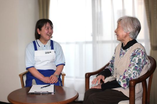 笑顔のスタッフと入居者が会話する居室