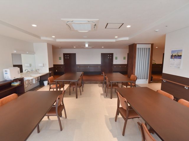 広々とした食堂の空間 共有スペース 広々としたダイニングエリアです。木の温もりを感じるテーブルが並び、利用者の方々が食事や交流を楽しめる設計となっています。