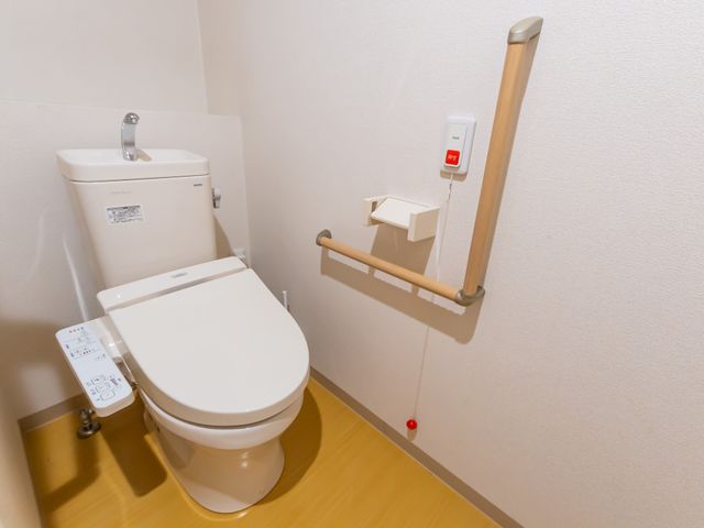 手すり完備のトイレ空間 トイレ 手すりや緊急呼び出しボタンが完備されたトイレで、安全な介護環境を提供しましょう。