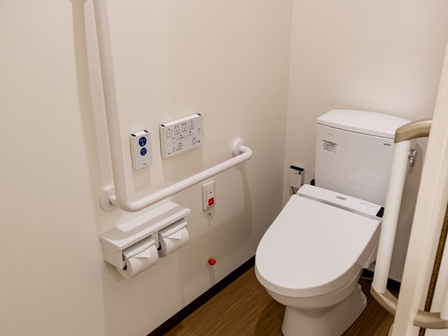 手すり付きのトイレ トイレ 手すりが設置された安全性の高いトイレです。清潔感ある木目調の床が特徴です。