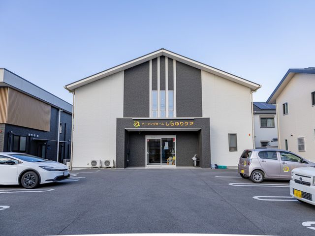 駐車スペースのある建物外観 外観 広い駐車スペースを備えたモダンな建物の前景です。利便性の高いアクセスを提供します。
