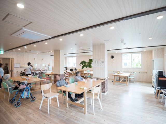 明るい広々としたダイニング 食堂 ゆったりしたテーブルが並ぶダイニングルームです。利用者の方々がお食事やコミュニケーションを楽しむ様子が伺えます。