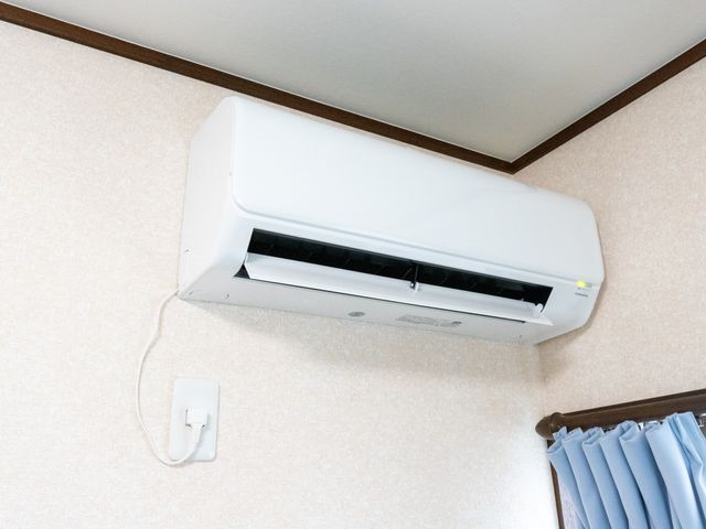 エアコンが取り付けられた壁 エアコン 快適な温度を保つためのエアコンが壁に設置されており、一年を通して快適にお過ごしいただけます。