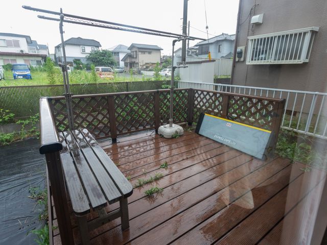 リラックスできるテラス テラス 雨のため木のテラスが濡れており、ベンチとテーブルでくつろぐのに心地よい空間です。