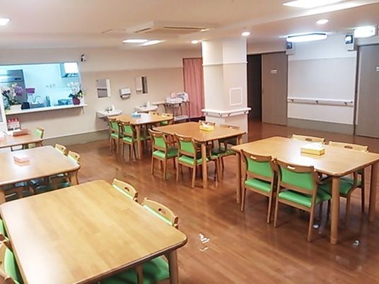 ４人掛けのテーブルと椅子が複数個所に置いてある施設内のリビングスペース