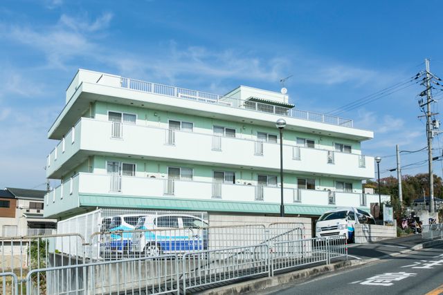 白い外壁の三階建て建物 晴れた空に映える、清潔感あふれる三階建ての白い建物です。見通しの良い立地にあり、快適な勤務環境をお探しの方に適しています。