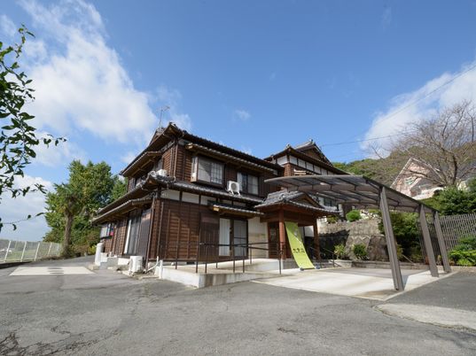 施設の写真 日本家屋風デザインの有料老人ホーム大黒荘の外観写真。広めの敷地内に植樹されている