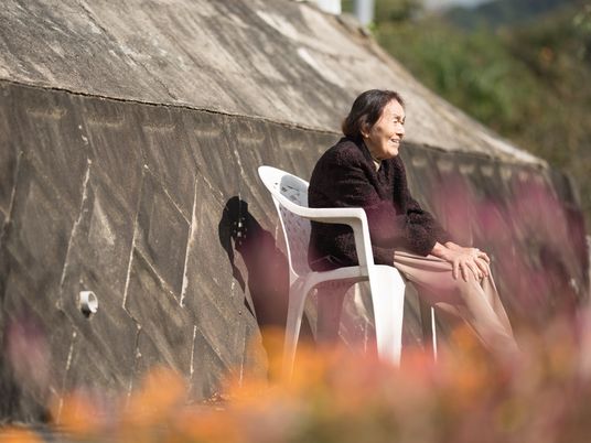 施設の写真 白い椅子に女性が一人で座り、微笑んでいる