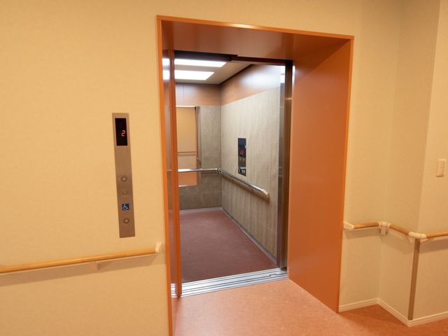 エレベーター前の廊下 エレベーター 手すりが廊下に沿って設置され、バリアフリー設計のエレベーター前です。移動のしやすさを考慮した環境です。