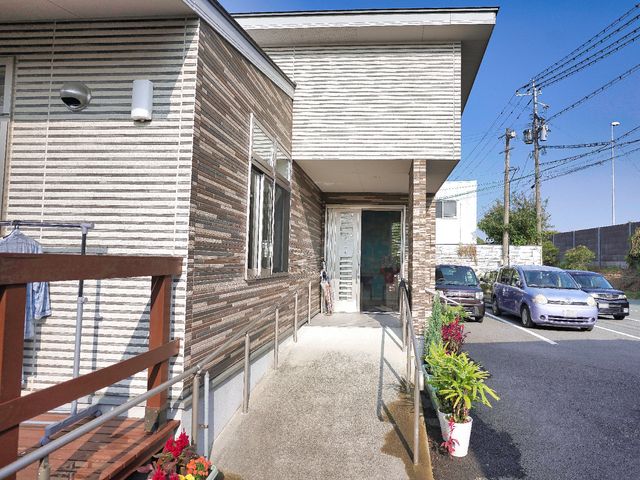 白い壁の建物入口 玄関 開放的な入口は、温かみのあるデザインで皆様をお迎えします。ここから新しい職場での一日が始まります。
