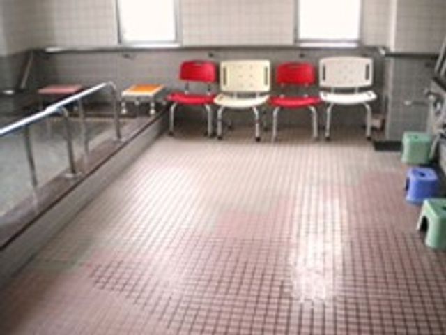 椅子が並んだ浴室 浴室 清潔で広々とした浴場では、椅子に座って安心して入浴できる環境が整っています。