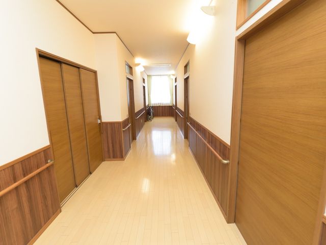 清潔感ある廊下 廊下 手すりを備えた広々とした廊下が一望でき、誰もが安心して歩ける配慮がされています。壁と床の色のコントラストも視認性を高めています。