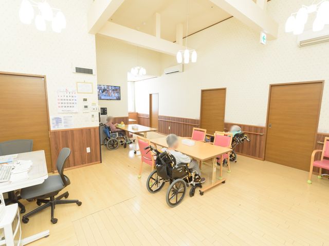 車椅子対応ダイニングルーム 休憩スペース 広々としたダイニングルームでは、車椅子の方々がゆったりと過ごしています。スタッフとのコミュニケーションも活発に行われている様子です。