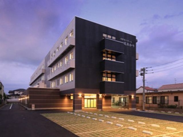 明るい照明の施設外観 外観 落ち着いた色合いで設計された外観は、温かみを感じさせる照明で夕暮れ時も安心感を与えます。