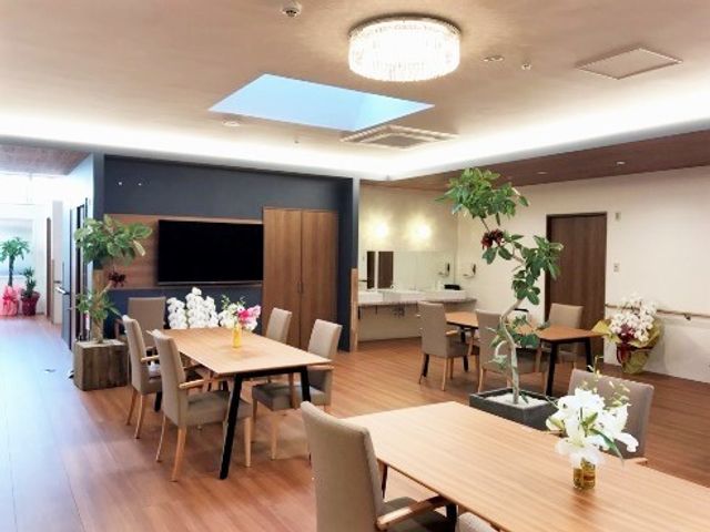 明るく広々した共用スペース リビング 共有スペースは清潔で明るく、ゆったりとした食事や憩いの場を提供しています。複数のテーブルが配置され、窓際の植物が爽やかな雰囲気を演出しています。