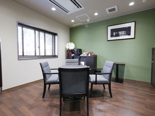 談話室の中央にグレーの座面をもつ椅子とテーブルが置かれている。天井にはエアコンと換気システムが埋め込まれている。