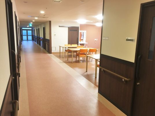 施設内の廊下と共有スペースの写真。小さなリビングと手すりがついた廊下の様子