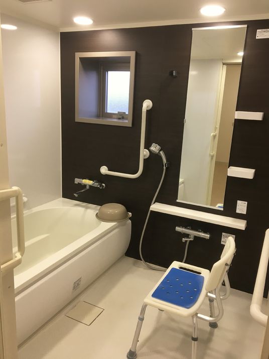 シャワーチェアが置いてある施設内の浴室の様子。手すりがついており立ち上がいりゃ移動をサポートしている