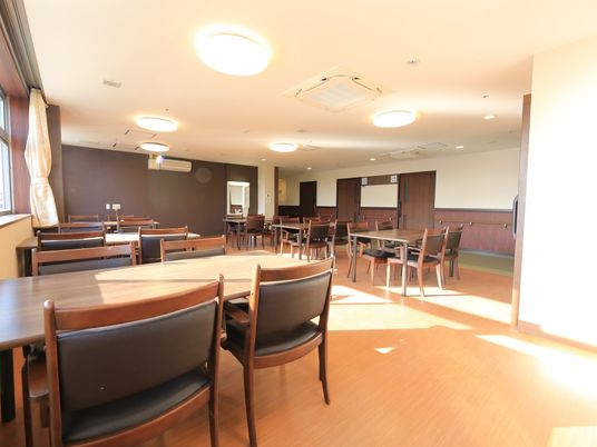 壁の一部がダークブラウンになっている広い食堂がある。壁と同系色の椅子とテーブルが並んでいる。仕切りはなく、廊下と直結している。