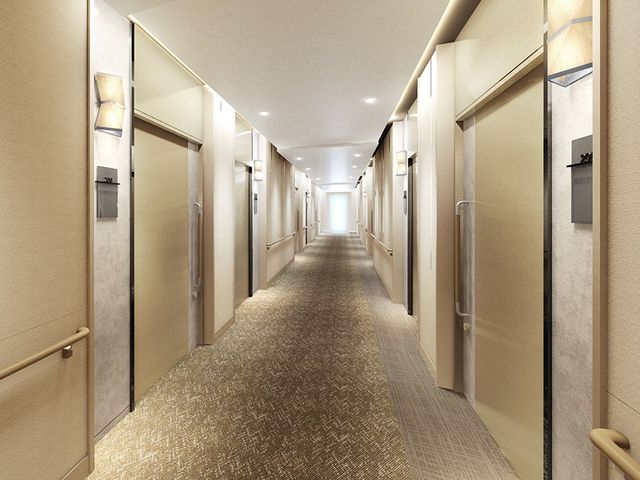 手すり付きの明るい廊下 通路 温かみのある照明と手すりが整った廊下は、安全にご利用いただけるよう配慮されています。適度な幅があり、ゆったりと歩くことができます。