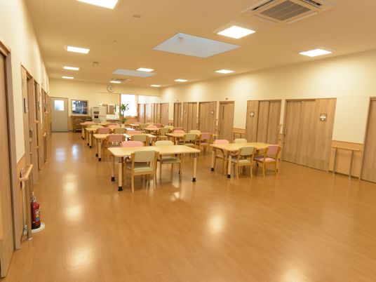 広いスペースに、テーブルが８台と椅子が多く置かれていて食堂として利用されている。奥の壁際には洗面台がある。