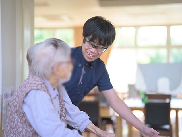 和やかな交流風景 リビング 広々とした空間で、スタッフと利用者の方が和やかに会話を楽しんでいます。自然光が差し込み、明るい雰囲気です。