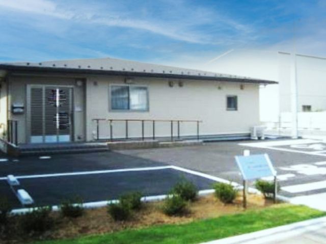駐車場のある建物 外観 広々としたスペースが確保され、車椅子利用者にもやさしい設計です。青空に映える建物です。