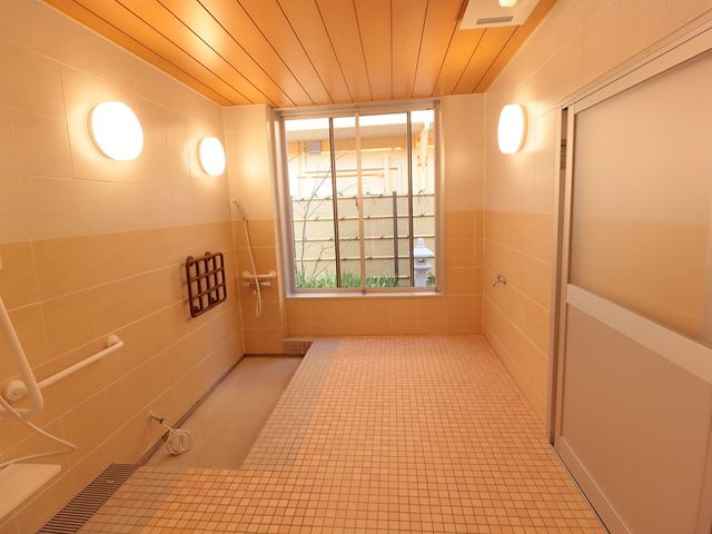 広々とした明るい浴室 浴室 自然光が差し込む浴室で、壁には手すりが設置されており、安全に配慮されています。