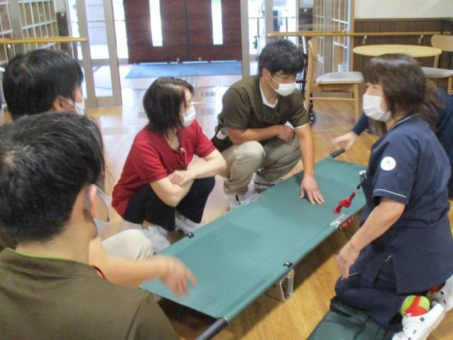 訓練風景の室内 機能訓練室 スタッフが協力して、安全な移動方法を学んでいる場面です。実践を通じて学べる環境が魅力です。