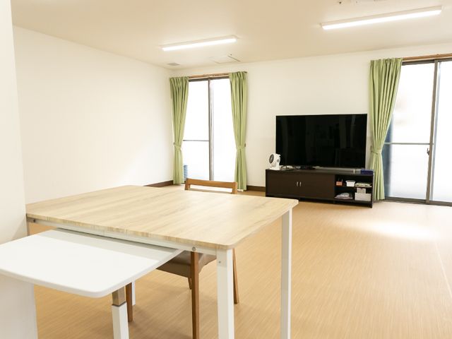 明るい居室の一角 共有スペース ゆったりとした居室には大型テレビと広窓があり、日々の暮らしを快適に過ごせるよう設えられています。