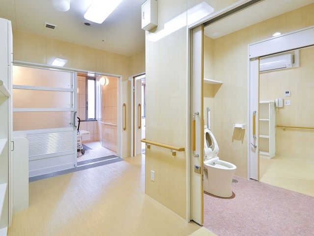 バリアフリーなトイレ設備 トイレ 手すりが設置された清潔で広々としたトイレ空間。安全に配慮された設計で、利用者の快適さを考えています。