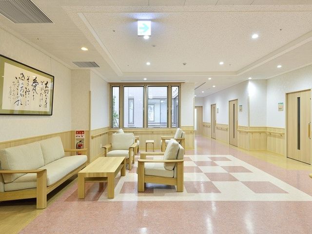 ゆったりした廊下 廊下 明るく清潔感のある休憩スペースが廊下に設けられ、安らぎを提供しています。ソファはゆとりを持って配置されており、くつろぎの時間を過ごせそうです。