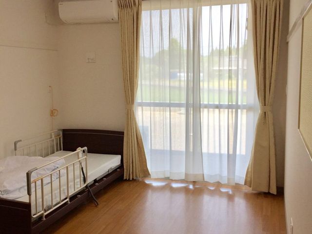 窓際にある居室 居室 窓から自然光が差し込む明るい居室です。介護ベッドが備え付けられ、快適な空間を提供しています。