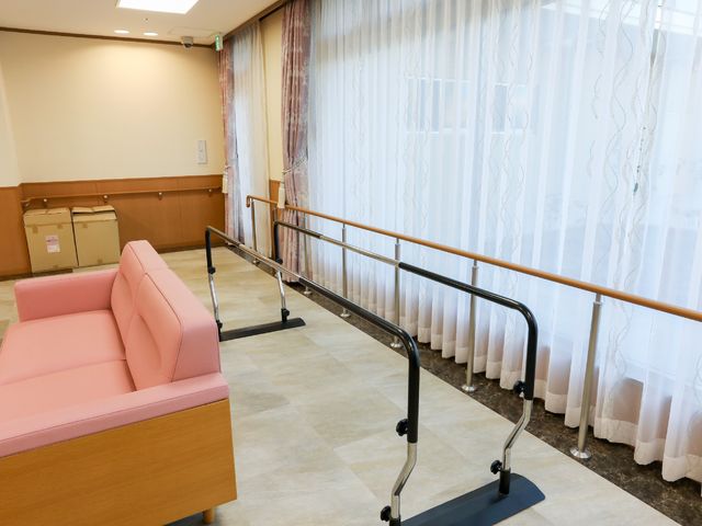 リハビリ用歩行器とソファ 共有スペース 安定した手すりが設置された歩行練習スペースです。快適な環境で体力維持向上が図れます。