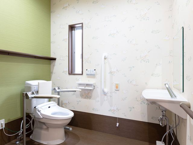 手すり付きのトイレ トイレ 広々としたトイレには手すりが設置され、安全に利用できる工夫がされています。窓からの自然光で明るい空間が魅力です。