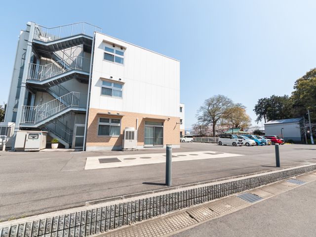 空と広々とした外観 外観 青空の下、広々とした建物の外観です。アクセスが良く、駐車スペースも充実しています。