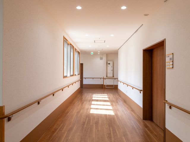 明るい手すり付き廊下 廊下   木目調の床と手すりが続く、明るく見通しのよい廊下です。出入口も分かりやすく、移動しやすい印象です。