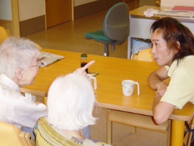会話を楽しむダイニング ダイニングルーム 明るいダイニングで、スタッフと利用者様が和やかに会話を楽しんでいます。