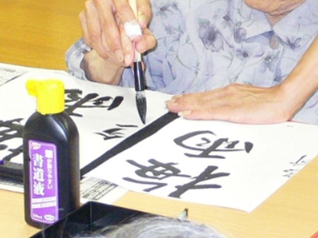 書道を楽しむ手元 多目的室 丁寧に字を書く手が見えます。書道を通じて、日々の生活に潤いを与える場です。