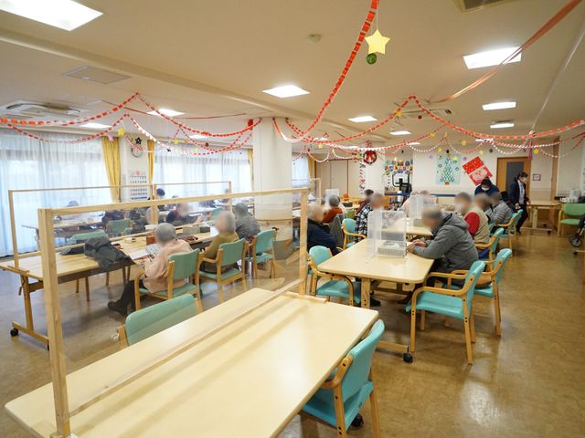 装飾付き共有ダイニング 共有スペース 広々としたダイニングルームで利用者同士がコミュニケーションをとっています。季節の装飾も心を和ませる工夫が感じられます。