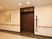 サムネイル 茶色い扉のエレベーターがある。操作パネルがあり、１階を表示している。壁に設置された手すりの上に絵が飾られている。