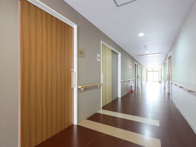 清潔感のある廊下の様子 廊下 安全に配慮された手すり付きの廊下は、明るく開放的な空間が広がり、快適な移動をサポートします。手すり沿いには各居室の番号が明示され、視認性が高まっています。